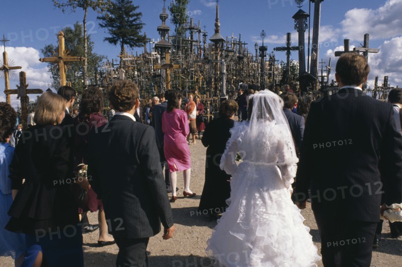 LITHUANIA, Hill of Crosses, Wedding group in front of hundreds of crosses and crucifix at ancient pilgrimage site near Siaulial.