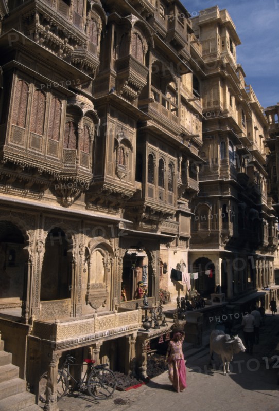 INDIA, Rajasthan, Jaisalmer, Patwon ki Haveli exterior with people and cattle seen on the path at the bottom