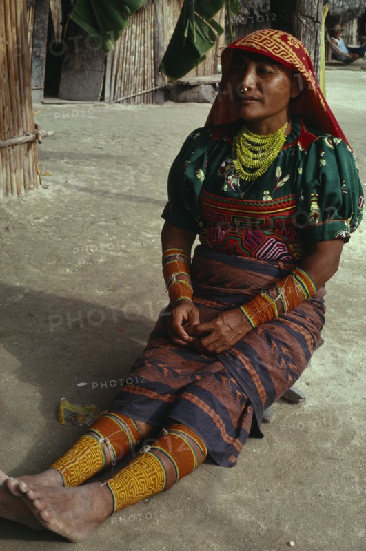 PANAMA, San Blas Islands, Kuna Indians, Kuna Indian woman wearing brightly coloured traditional layered applique mola  multi strand bead necklace  bead arm and leg bands and gold nose ring. Cuna Caribbean American Central America Classic Classical Colored Female Women Girl Lady Hispanic Historical Latin America Latino Older Panamanian West Indies