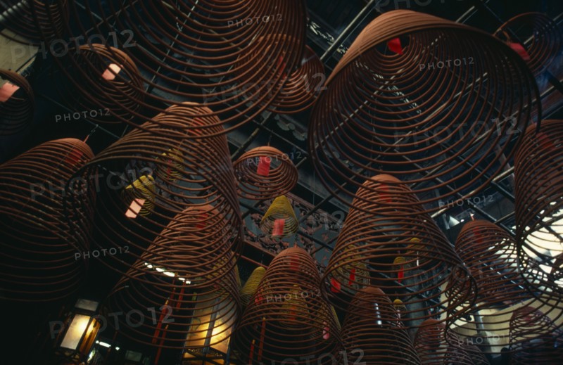 HONG KONG, Central District, Man Mo Temple, Spiral cones of incense hanging from roof of the Man Mo or warlord temple.  The warlord god is Kwan Tai and is patron of both police and gangsters.  A historical figure from the Three Kingdoms period (AD 220-265) he was deified as a Taoist symbol of integrity and loyalty.  The temple is dedicated jointly to Kwan Tai and the god of literature.