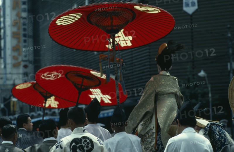JAPAN, Honshu, Kyoto, "Gion Festival.  Four days before the festival climax the ‘chigo’ the pageboy of the god to whom the festival is dedicated, dressed in the silk robes of a Heian nobleman is taken on a white horse to a ceremony of exorcism and purification in the Yasaka shrine.  He is shielded from the sun by red parasols carried by attendants."
