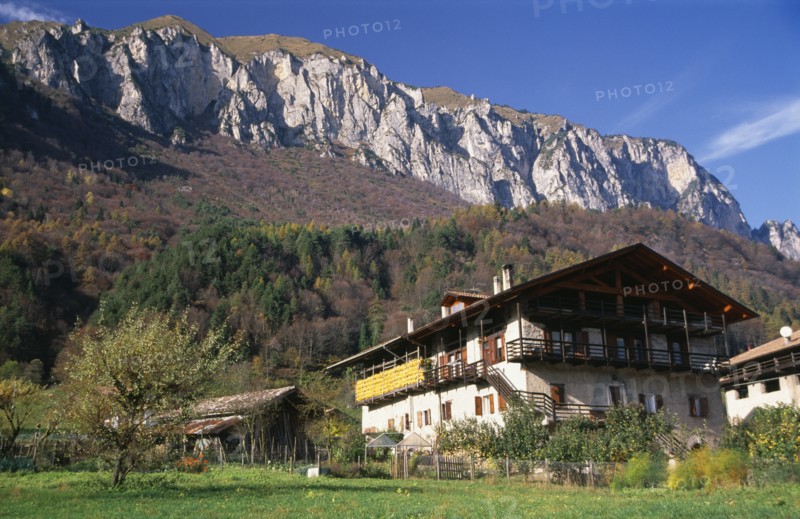 ITALY, Trentino-Alto Adige, Lake Garda Area, "Alpine farmstead near Lago di Tenno.  Traditional building with over hanging roof and balcony, outbuildings and mountain backdrop."