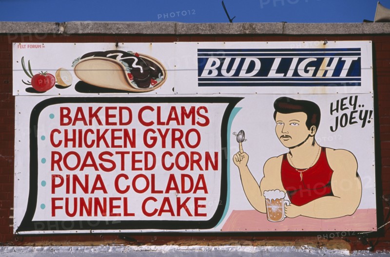USA, New York, New York City, Coney Island.  Sign for cafe / bar listing food and drink  with painted illustrations of drinking man spinning a clam shell on his finger and American slang phrase ‘Hey Joey’.