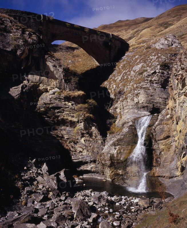 FRANCE, Aquitaine, Pyrenees Atlantiques, Defile de Tourmont.  Gave de Brousset waterfall flowing from rocks into pool below with arched bridge above.