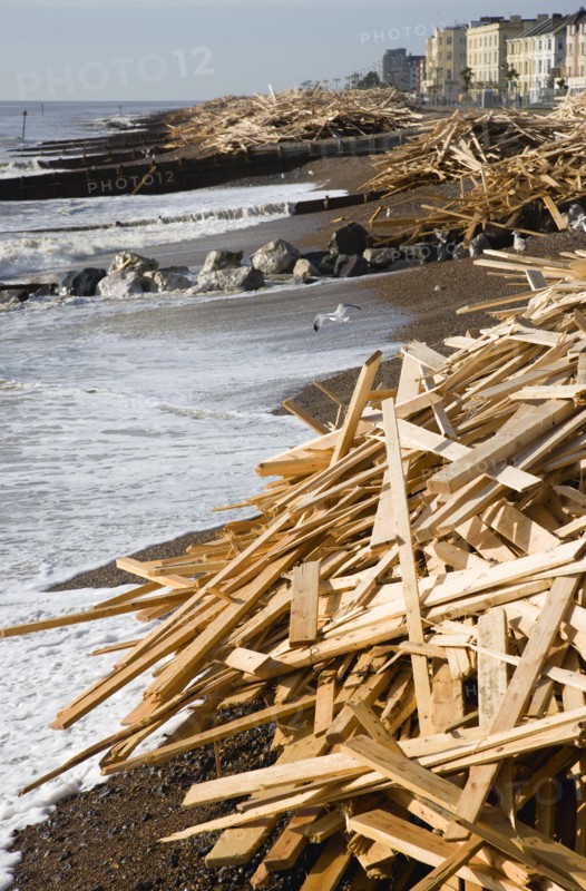 ENGLAND, West Sussex, Worthing, Timber washed up on the beach from the Greek registered Ice Princess which sank off the Dorset coast on 15th January 2008. Waves crash against the groynes with seafront houses beyond