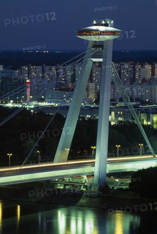 SLOVAKIA, Bratislava, Novy Most (New Bridge) topped with restaurant over the River Danube with views towards Petrzalka tower blocks at night with light trails from passing traffic below.