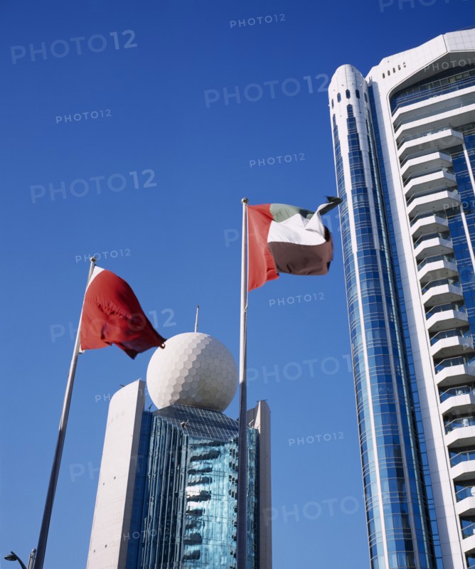 UAE, Dubai, Deira, Etisalat Building on Dubai Creek with flag poles in foreground.