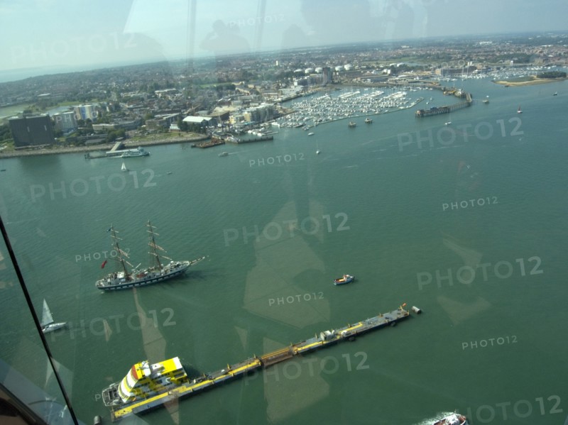 ENGLAND, Hampshire, Portsmouth, Gunwharf Quays. The Spinnaker Tower. View looking out of a glass window on the observation deck across the harbour towards Gosport with Ferries and a tall ship seen on water