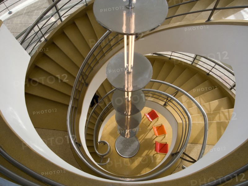 ENGLAND, East Sussex, Bexhill-on-Sea, The De La Warr Pavilion. Interior view down the helix staircase with chrome Bauhaus globe lamps. Three colourful chairs seen at the bottom