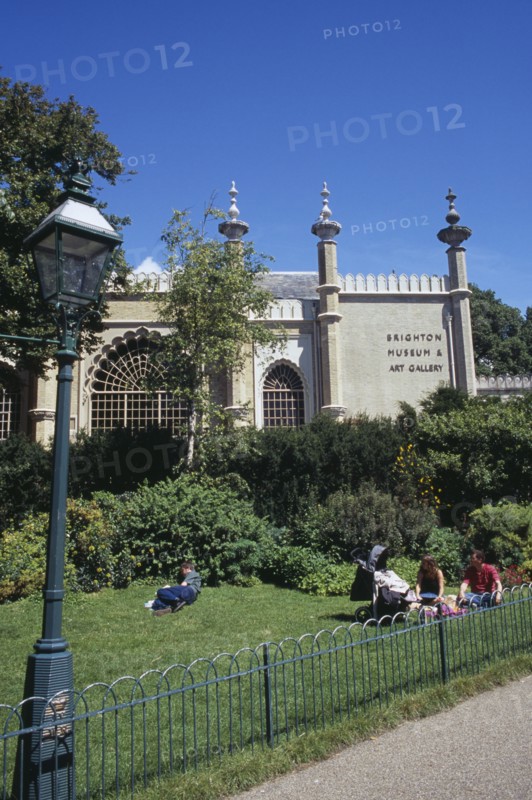 ENGLAND, East Sussex, Brighton, Brighton Museum and Art Gallery seen from The Royal Pavilion gardens with families sitting on the grass