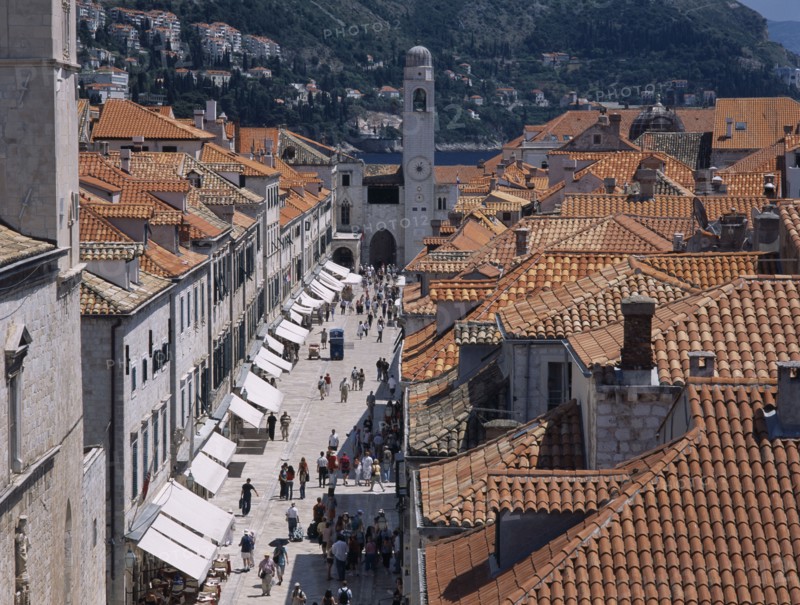 CROATIA, Dalmatia, Split, "Elevated view over terracotta tiled rooftops and Stradun, the main street in the Old City which is lined with cafes and bars leading towards The Franciscan Monastery Church."