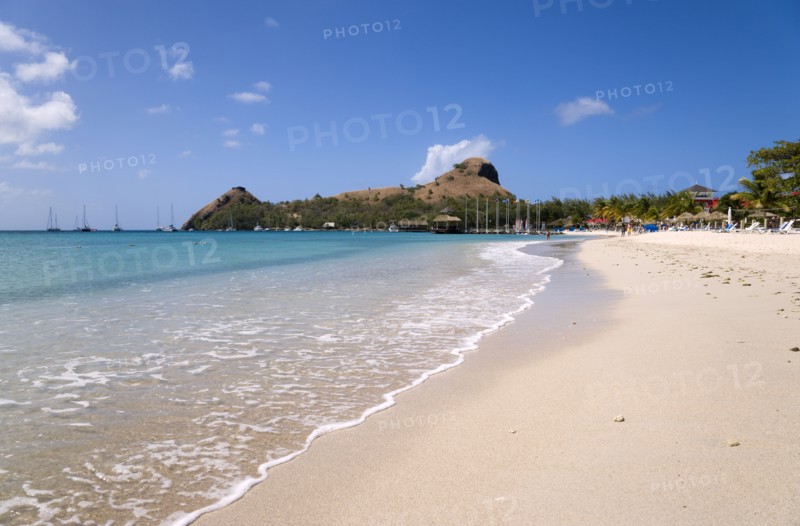 WEST INDIES, St Lucia, Gros Islet , The beach at Sandals Grande St Lucian Spa and Beach Resort hotel with Pigeon Island National Historic Park beyond
