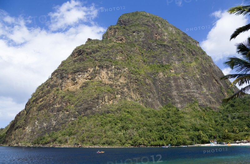 WEST INDIES, St Lucia, Soufriere , Val des Pitons The white sand beach at the Jalousie Plantation Resort Hotel with the volcanic plug of Petit Piton beyond and tourists on sunbeds beneath palapa sun shades