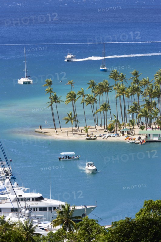 WEST INDIES, St Lucia, Castries , Marigot Bay Yachts at anchor beyond the small coconut palm tree lined beach of the Marigot Beach Club sitting at the entrance
