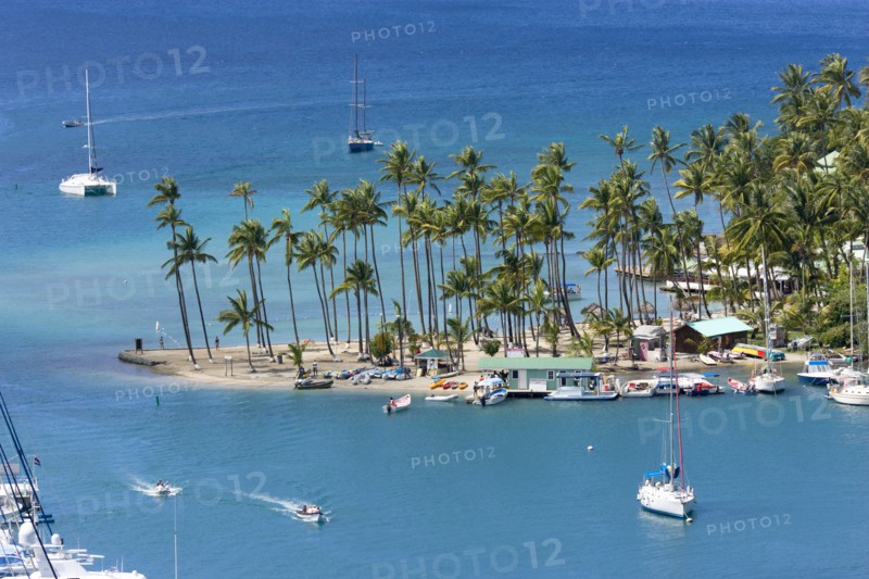 WEST INDIES, St Lucia, Castries , Marigot Bay Yachts at anchor beyond the small coconut palm tree lined beach of the Marigot Beach Club sitting at the entrance