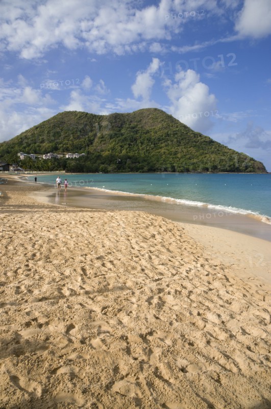 WEST INDIES, St Lucia, Gros Islet, Reduit Beach in Rodney Bay during the early morning with tourists walking by the waterline