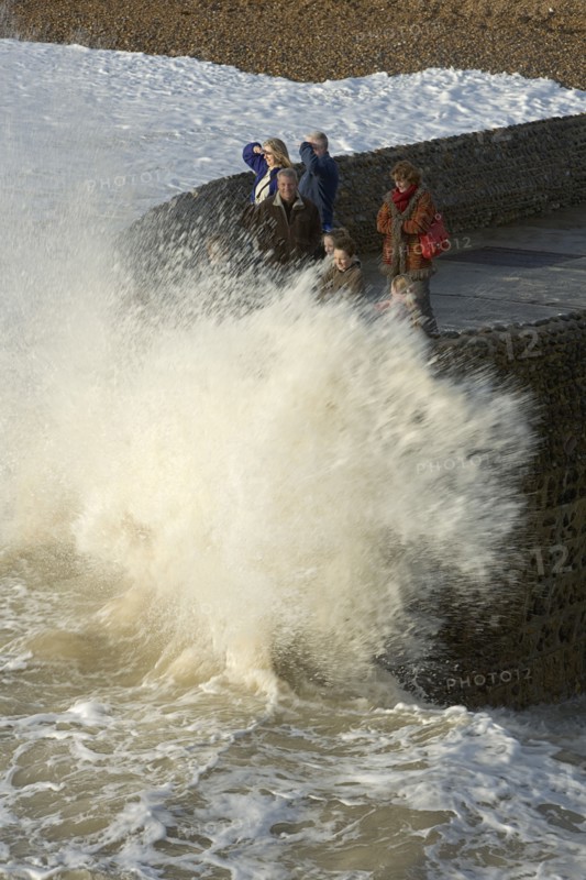 ENGLAND, East Sussex, Brighton, Waves crashing onto beach and groyne with people getting wet.