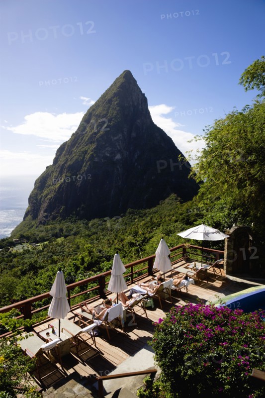 WEST INDIES, St Lucia, Soufriere , Val des Pitons Tourists sunbathing on the sun deck beside the pool at Ladera Spa Resort Hotel overlooking Petit Piton volcanic plug and Jalousie beach