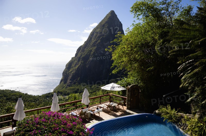 WEST INDIES, St Lucia, Soufriere , Val des Pitons Tourists sunbathing on the sun deck beside the pool at Ladera Spa Resort Hotel overlooking Petit Piton volcanic plug and Jalousie beach