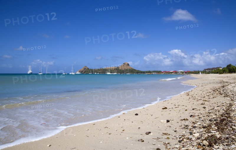 WEST INDIES, St Lucia, Gros Islet , Pigeon Island National Historic Park seen from a nearby beach on a causeway to the island with yachts at anchor in Rodney Bay