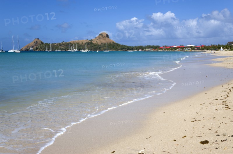WEST INDIES, St Lucia, Gros Islet , Pigeon Island National Historic Park seen from a nearby beach on a causeway to the island with yachts at anchor in Rodney Bay
