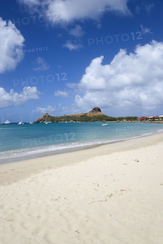 WEST INDIES, St Lucia, Gros Islet , Pigeon Island National Historic Park seen from a nearby beach on a causeway to the island with yachts at anchor in Rodney Bay