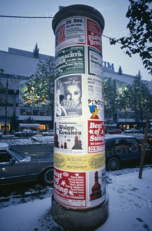 GERMANY, Berlin, Poster pillar along Kurfurstendamm commercial street in West Berlin at winter time