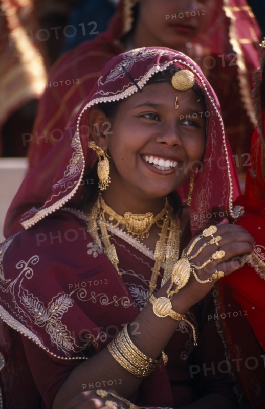 INDIA, Rajasthan, Bikaner, Portrait of a young girl dancer smiling wearing traditional jewellery at the Camel Festival