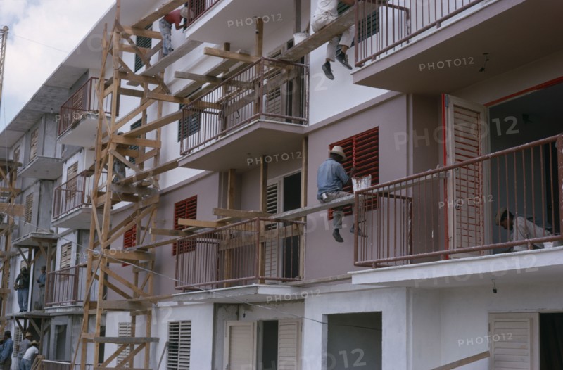 CUBA, Industry, Construction workers and painters on wooden scaffolding working on muli-storey building exterior.