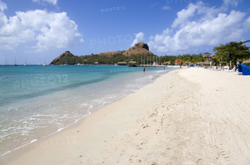 WEST INDIES, St Lucia, Gros Islet , The beach at Sandals Grande St Lucian Spa and Beach Resort hotel with Pigeon Island National Historic Park beyond