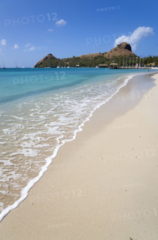 WEST INDIES, St Lucia, Gros Islet , The beach at Sandals Grande St Lucian Spa and Beach Resort hotel with Pigeon Island National Historic Park beyond