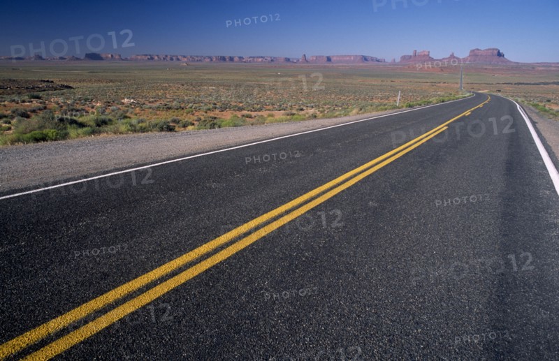 USA, Arizona , Monument Valley, "View from US Highway 163 across empty stretch of road leading to the valley with red mesas, buttes and pinnacles of rock seen in the distance"