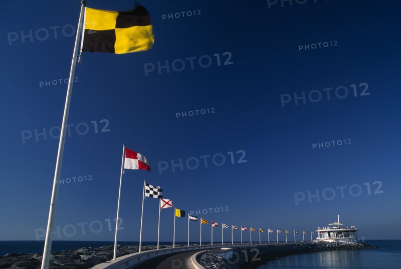UAE, Dubai, Jumeirah Beach.  Curving marina wall and line of flags.