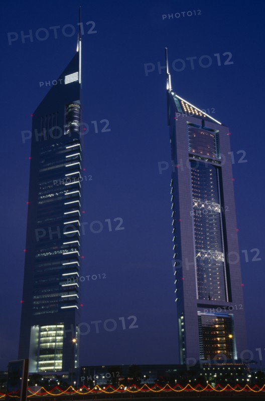 UAE, Dubai , Emirates Tower illuminated at night with coloured lights in the foreground.