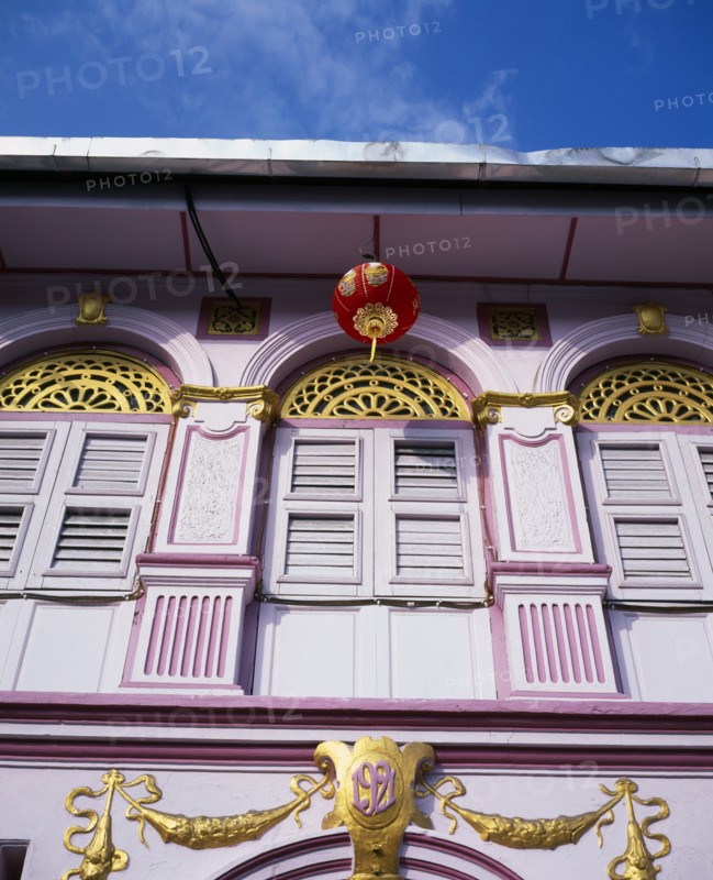 MALAYSIA, Penang, Georgetown, Pink and gold painted shopfront with wooden window shutters and red and gold Chinese lantern hanging from the roof for Chinese New Year.