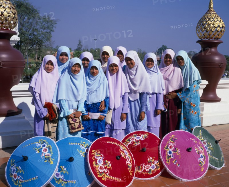 THAILAND, North, Chiang Mai, "Group of young Muslim Thai women standing behind blue, red, pink and green painted parasols at the Royal Flora Expo."