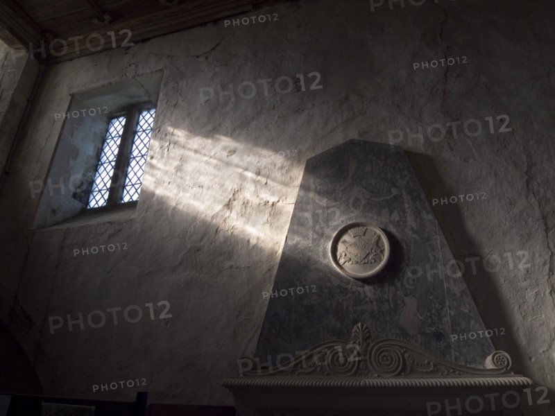 ENGLAND, West Sussex, Boxgrove, Boxgrove Priory Church of St Mary and St Blaise. Interior view of  light shining through small window onto a wall and marble monument.