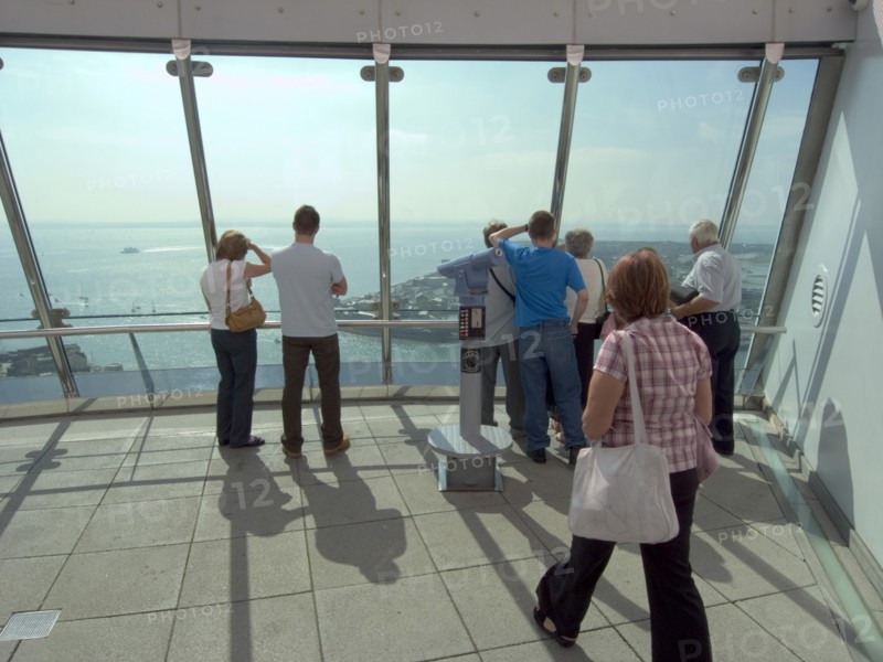 ENGLAND, Hampshire, Portsmouth, "Gunwharf Quays. The Spinnaker Tower. Interior view with visitors looking out of glass windows on the top observation deck, providing a 320° view of the city of Portsmouth, the Langstone and Portsmouth harbours, and a viewing distance of 37 kilometres (23 miles)"