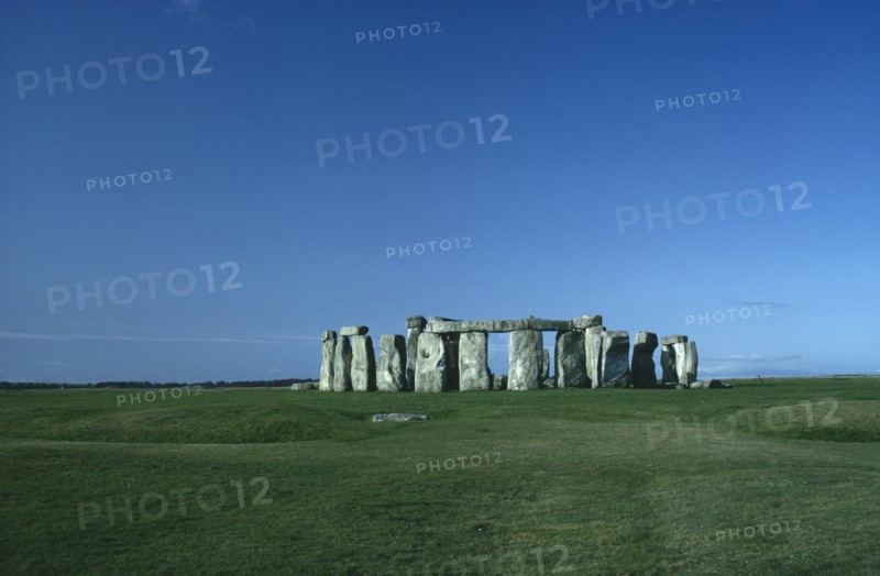 ENGLAND, Wiltshire, Stonehenge, View across the grass on Salisbury Plain towards the standing stones.