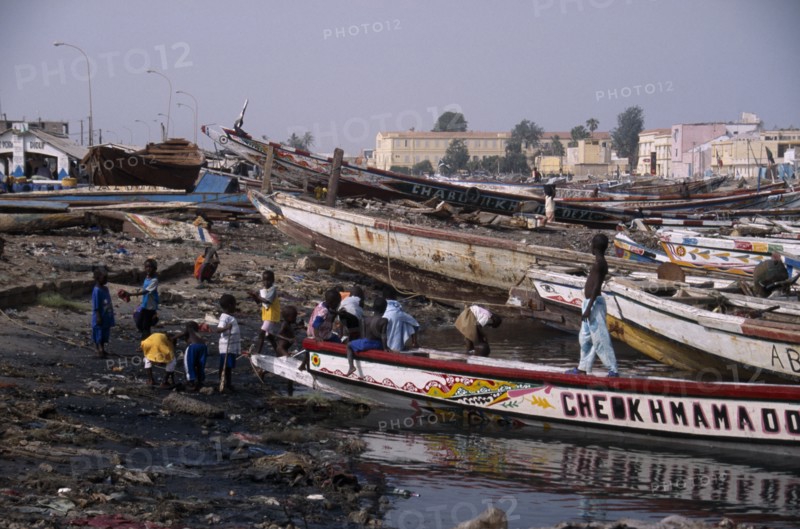 SENEGAL, St Louis, Children playing on shore next to beached boats.