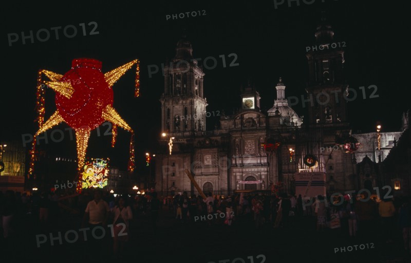MEXICO, Mexico City, Crowds gathered in the Plaza de la Constitucion or Zocalo at Christmas with illuminated decorations at night.