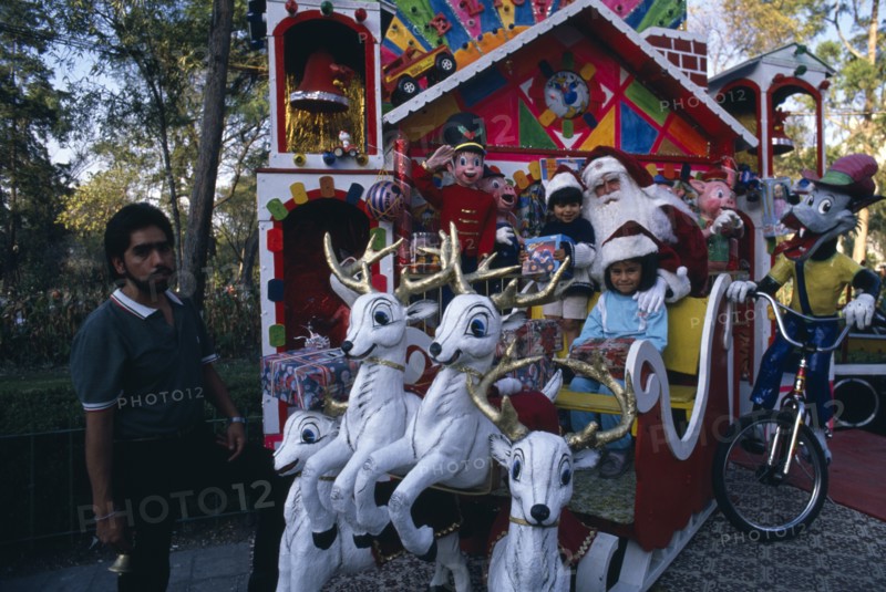 MEXICO, Mexico City, Children visiting Father Christmas in his sleigh in Mexico City Park