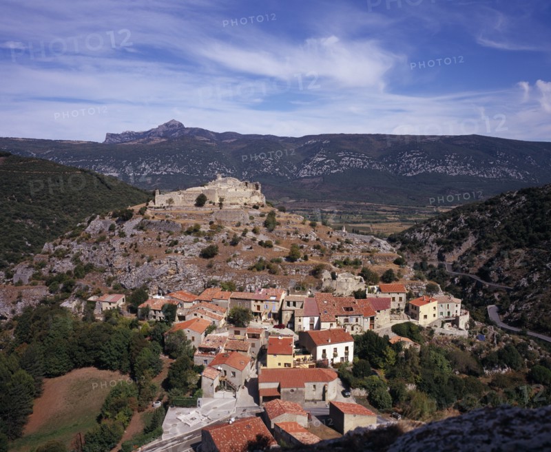 FRANCE, Languedoc-Roussillon, Aude, Fenouillet.  View from Chateau Sabarda over streets and red tiled rooftops of village houses with ruins of Chateau St Pierre on hillside above.