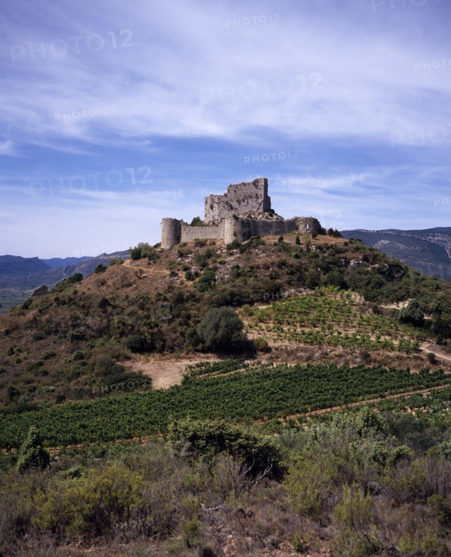 FRANCE, Languedoc-Roussillon, Aude, Chateau de Aguilar.  Ruins of twelth Century Cathar castle set on hillside in the commune of Tuchan.  Inner keep surrounded by outer thirteenth century fortification. Vines growing in valley below.
