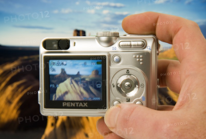 TECHNOLOGY, Media, Photography, Digital camera held in a hand with an image on the screen and in the background of Monument Vally (studio shot with camera held in front of a print)