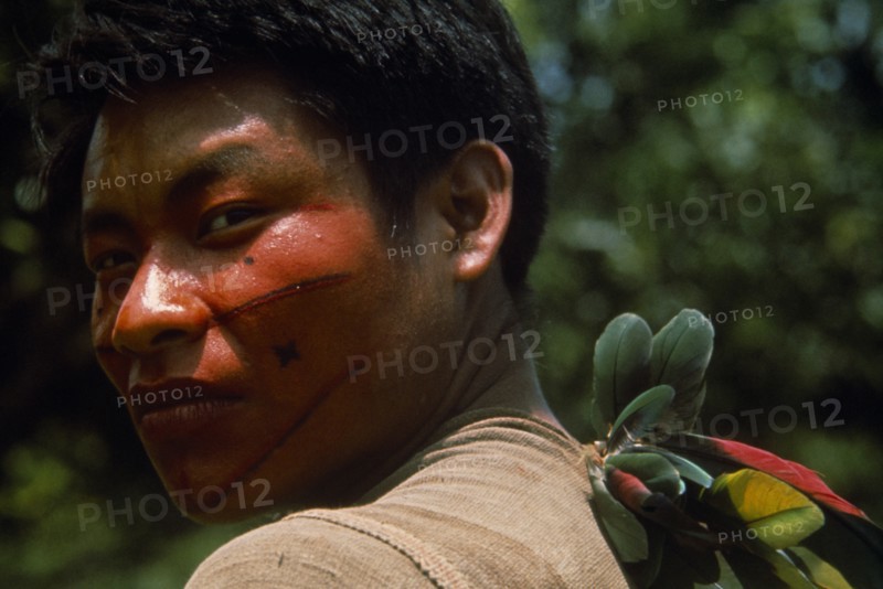 20088952 PERU  Rio Pachitea Portrait of young Campa tribesman with red and black painted face looking towards camera over his shoulder.