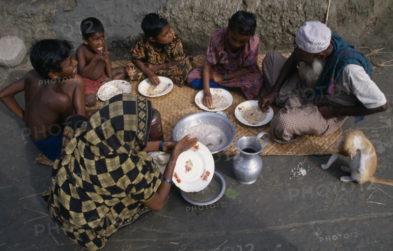 BANGLADESH, Khulna, Char Kukuri Mukuri, "Family having breakfast of rice, seated on mat laid on ground and eating with their right hands."
