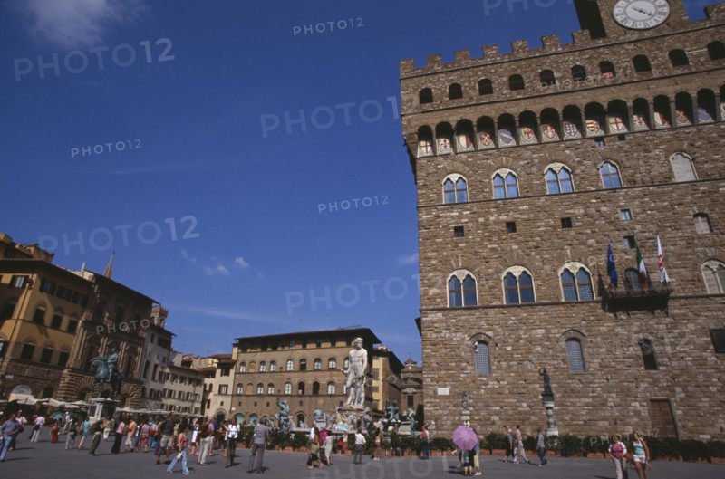 ITALY, Tuscany, Florence, Piazza della Signoria. Palazzo Vecchio with replica of the statue of David by Michelangelo .Tourists gathered on the ground