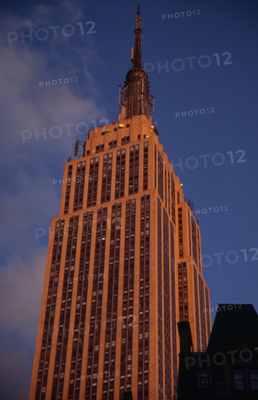 USA, New York, New York City, "Part view of the Empire State Building from 7th Avenue / West 31st Street.  Art Deco, steel framed building with radio and TV mast completed in 1931. Deep orange light.   Designed by architect William Lamb of Shreve, Lamb and Harmon Associates."