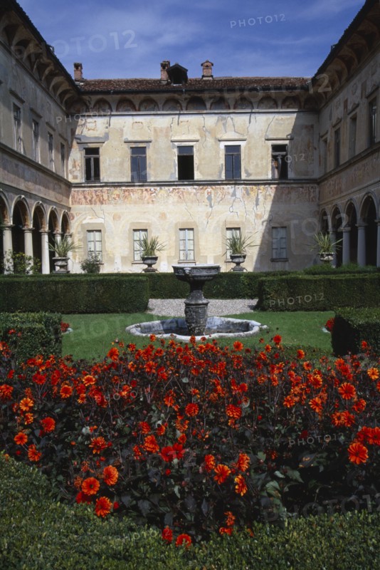 ITALY, Lombardy, Bisuschio, Villa Cicogna Mozzoni east of Lake Maggiore.  Exterior of Renaissance villa built between 1400 -1500 by the Mozzoni family.  Water feature and dahlias in foreground.